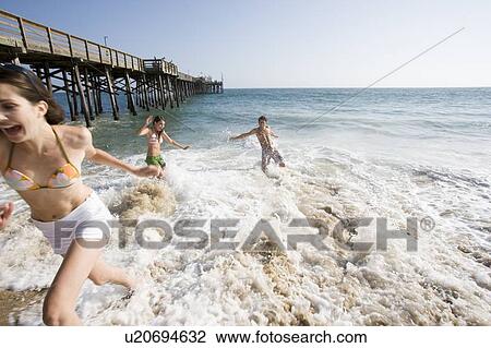 Stock Image - Young adult people having fun on beach, Side View, Front View. Fotosearch