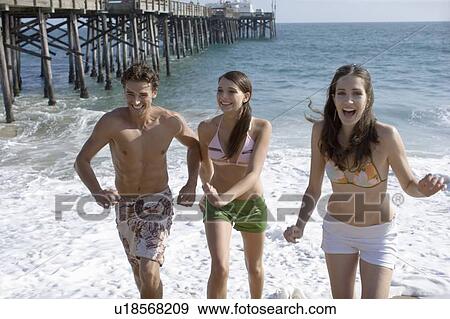 Stock Photo - Young adult people having fun on beach, Front View. Fotosearch