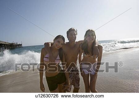 Stock Photograph - Young adult people smiling on beach, Front View. Fotosearch