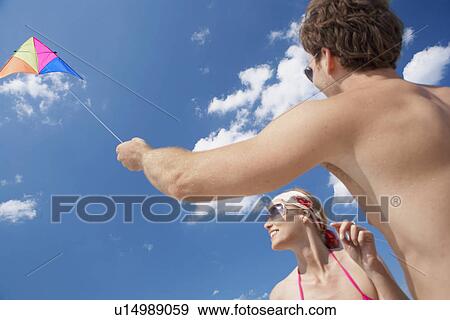 Young couple flying kite (low angle view) View Large Photo Image Stock Photo - Young couple flying kite (low angle view). Fotosearch