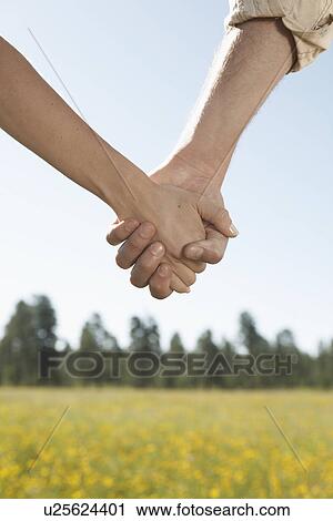 Young couple holding hands in a field of wildflowers (focus on hands) View Large Photo Image Stock Image - Young couple holding hands in a field of wildflowers (focus on hands). Fotosearch