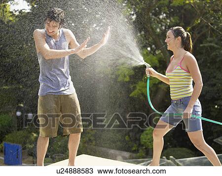 Young couple playing with water hose View Large Photo Image Stock Image - Young couple playing with water hose. Fotosearch