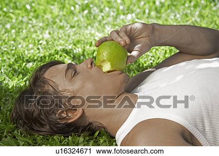 Young Man Eating Apple on Lawn View Large Photo Image Stock Image - Young Man Eating Apple on Lawn. Fotosearch