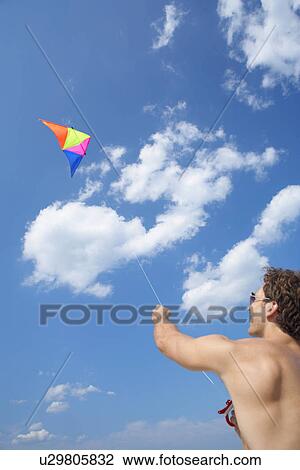 Young man flying kite View Large Photo Image Stock Image - Young man flying kite. Fotosearch