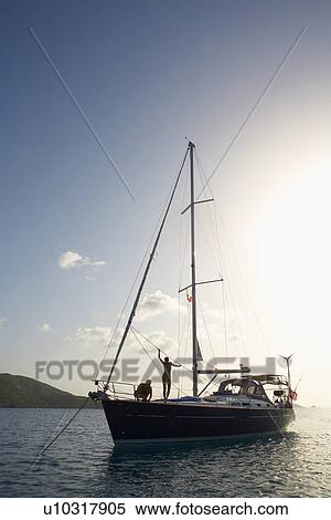 Stock Photography - Mid adult couple on sailboat. Fotosearch