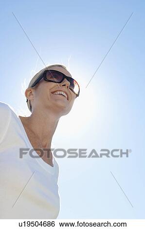 Mature woman wearing sunglasses (low angle view) View Large Photo Image Stock Photograph - Mature woman wearing sunglasses (low angle view). Fotosearch