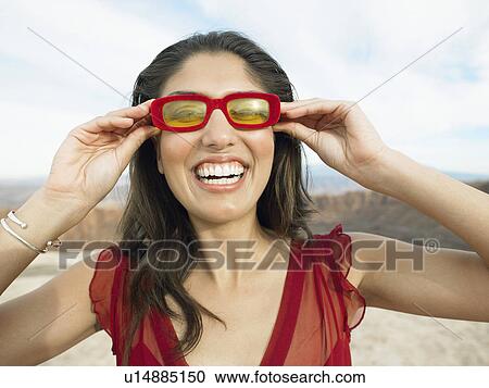 Stock Image - Mid adult woman trying silly sunglasses on, portrait. Fotosearch