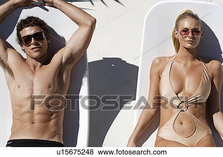 Young Couple Sunbathing on Lounge Chairs View Large Photo Image Stock Photo - Young Couple Sunbathing on Lounge Chairs. Fotosearch