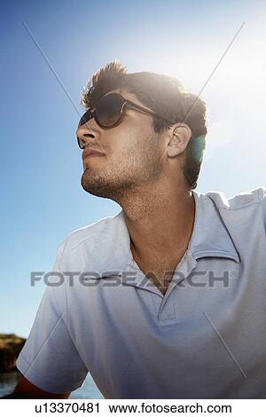 Young man in sunglasses looking up (low angle view) View Large Photo Image Stock Image - Young man in sunglasses looking up (low angle view). Fotosearch