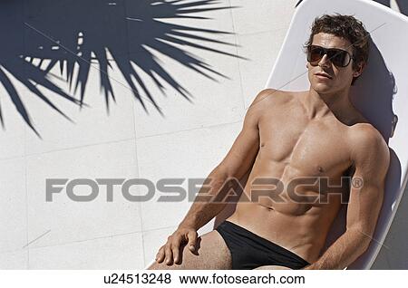 Stock Photo - Young Man Sunbathing on Lounge Chair. Fotosearch