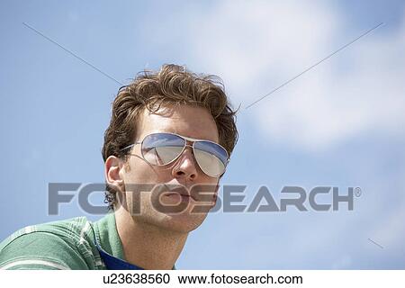 Young man wearing sunglasses (low angle view) View Large Photo Image Stock Image - Young man wearing sunglasses (low angle view). Fotosearch