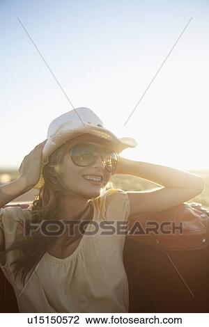 Young woman holding cowboy hat in convertible View Large Photo Image Stock Image - Young woman holding cowboy hat in convertible. Fotosearch