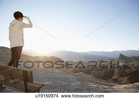 Young woman standing on bench and looking at view in desert, Death Valley, California, USA View Large Photo Image Picture - Young woman standing on bench and looking at view in desert, Death Valley, California, USA. Fotosearch