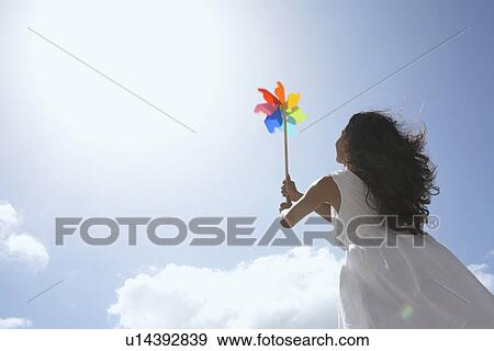 Young woman with pinwheel against sky (low angle view) View Large Photo Image Stock Photo - Young woman with pinwheel against sky (low angle view). Fotosearch