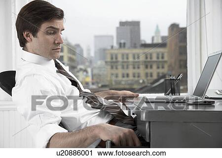 Businessman with laptop opening desk drawer View Large Photo Image Stock Image - Businessman with laptop opening desk drawer. Fotosearch