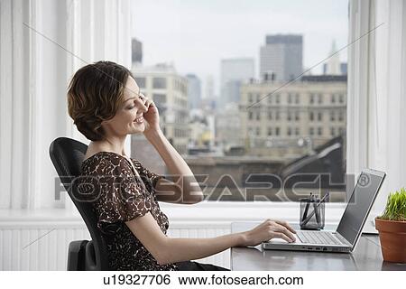 Businesswoman talking on the phone and using laptop View Large Photo Image Stock Photograph - Businesswoman talking on the phone and using laptop. Fotosearch