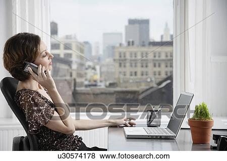 Businesswoman talking on the phone at desk View Large Photo Image Stock Photo - Businesswoman talking on the phone at desk. Fotosearch