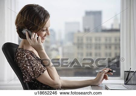 Businesswoman talking on the phone at desk View Large Photo Image Stock Photograph - Businesswoman talking on the phone at desk. Fotosearch