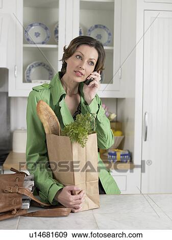 Mid adult woman with bag of groceries talking on phone View Large Photo Image Stock Photo - Mid adult woman with bag of groceries talking on phone. Fotosearch