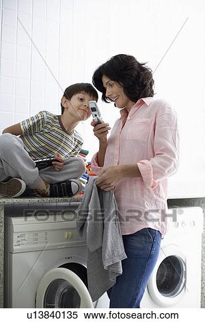 Mother and son text messaging in laundry room View Large Photo Image Stock Photography - Mother and son text messaging in laundry room. Fotosearch