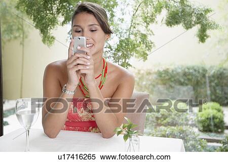Stock Photography - Woman reading text message at dining table. Fotosearch