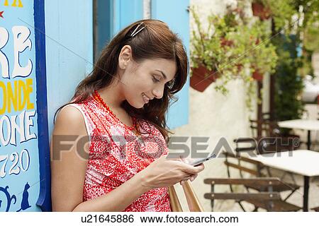 Woman text messaging outside café View Large Photo Image Stock Photograph - Woman text messaging outside café. Fotosearch