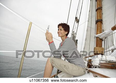 Woman using cell phone in sail boat View Large Photo Image Stock Photograph - Woman using cell phone in sail boat. Fotosearch