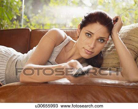 Young woman using remote control on sofa View Large Photo Image Stock Image - Young woman using remote control on sofa. Fotosearch