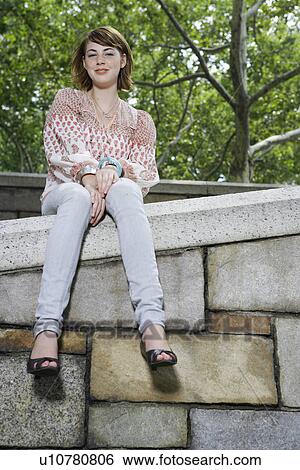 Portrait of teenage girl on sitting on stone wall (low angle view) View Large Photo Image Stock Photograph - Portrait of teenage girl on sitting on stone wall (low angle view). Fotosearch