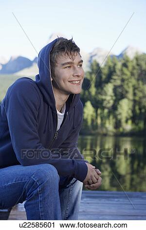 Stock Image - Teenage boy by lake, Cape Town, South Africa. Fotosearch