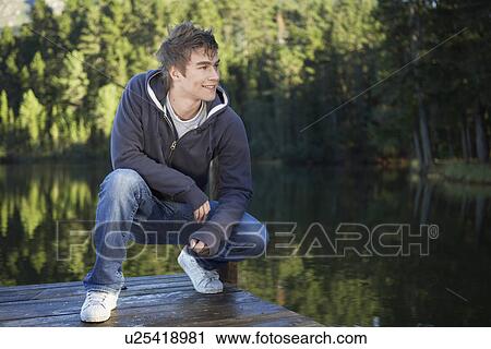 Teenage boy crouching on jetty View Large Photo Image Stock Image - Teenage boy crouching on jetty. Fotosearch
