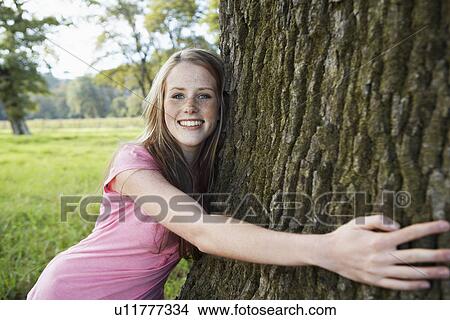 Picture - Teenage girl hugging tree. Fotosearch