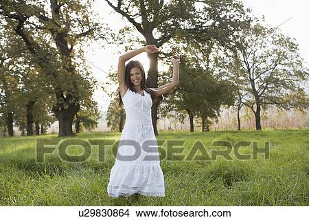 Picture - Teenage girl in white dress in field. Fotosearch