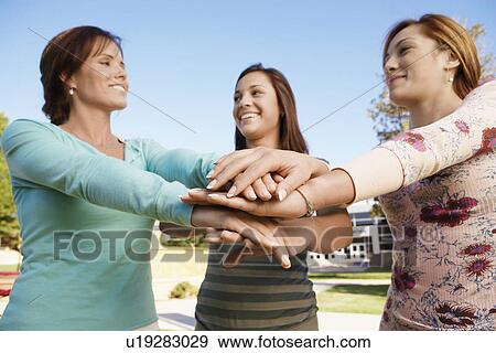 Three young women putting hands together View Large Photo Image Stock Photo - Three young women putting hands together. Fotosearch