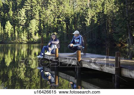 Stock Photography - Two teenage boys talking on jetty, Cape Town, South Africa. Fotosearch