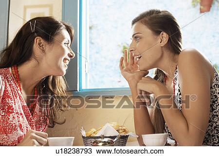 Two women talking at dining table View Large Photo Image Stock Image - Two women talking at dining table. Fotosearch