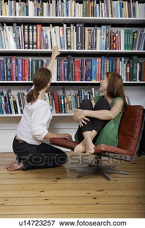 Two women talking by book shelf View Large Photo Image Stock Photo - Two women talking by book shelf. Fotosearch
