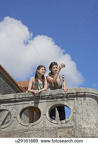 Two Young Women Photographing on Balcony View Large Photo Image Stock Photo - Two Young Women Photographing on Balcony. Fotosearch