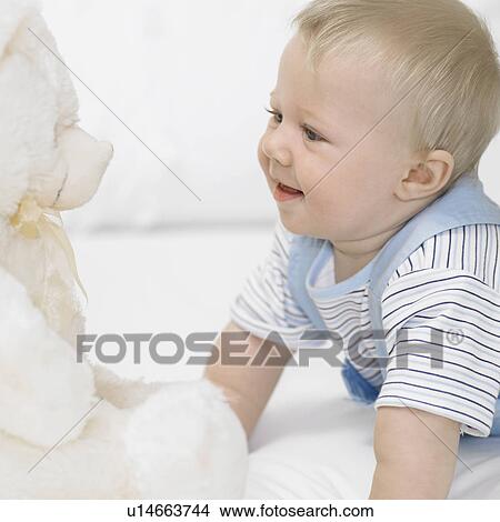 Baby boy (1-2) looking at teddy bear View Large Photo Image Picture - Baby boy (1-2) looking at teddy bear. Fotosearch