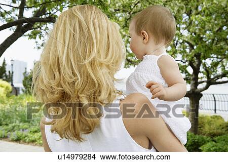 Picture - Mother carrying baby girl (rear view). Fotosearch