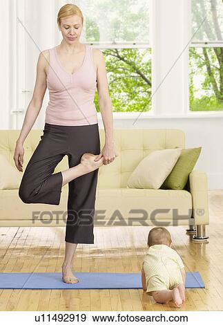 Stock Photo - Mother Doing Yoga near Baby Boy. Fotosearch