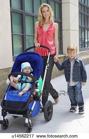 Mother walking on sidewalk with son and daughter View Large Photo Image Stock Photo - Mother walking on sidewalk with son and daughter. Fotosearch