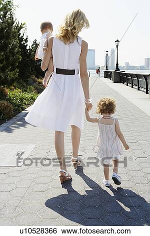 Stock Photograph - Mother walking with two daughters (rear view). Fotosearch