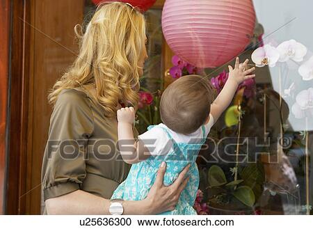 Mother with baby girl looking at window display View Large Photo Image Stock Image - Mother with baby girl looking at window display. Fotosearch