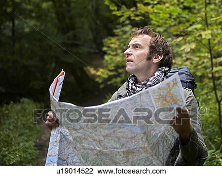 Stock Image - Male Hiker Reading Map in Forest. Fotosearch