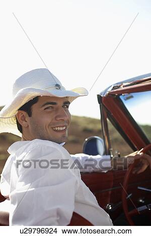 Picture - Young man in cowboy hat driving convertible. Fotosearch