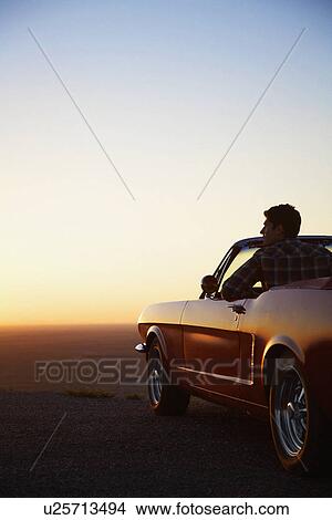 Picture - Young man looking at sunset in convertible, Arizona, USA. Fotosearch