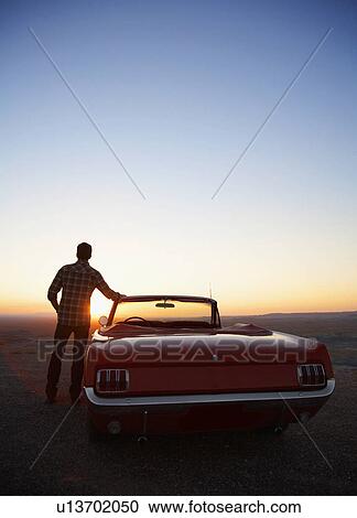 Young man standing by convertible and looking at sunset, Arizona, USA View Large Photo Image Stock Image - Young man standing by convertible and looking at sunset, Arizona, USA. Fotosearch