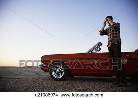 Young man with convertible photographing at sunset View Large Photo Image Picture - Young man with convertible photographing at sunset. Fotosearch