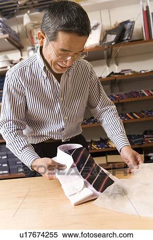 Stock Photography - A Mature Adult Man Putting a Folded Shirt into a Bag, Front View. Fotosearch